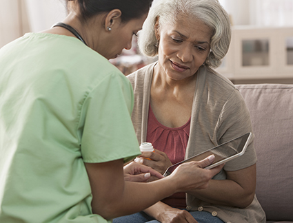 Nurse explaining to elderly patient on tablet